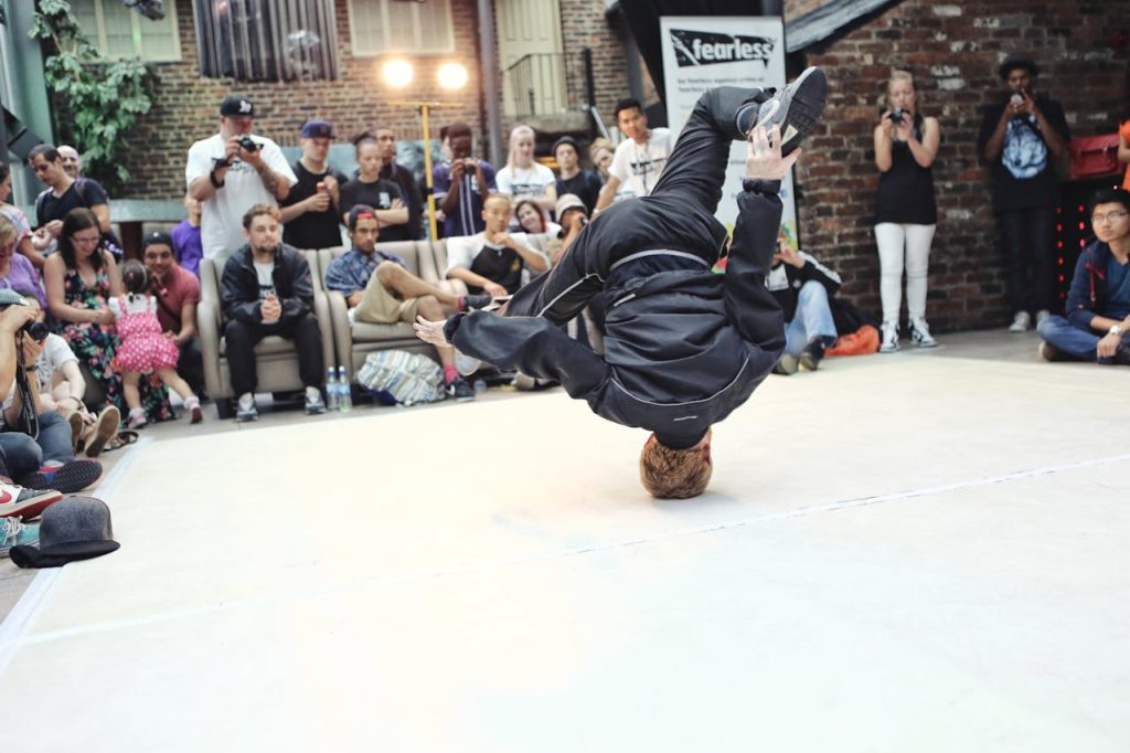 A vibrant breakdancer showcases an acrobatic move during a street performance, capturing the crowds attention.