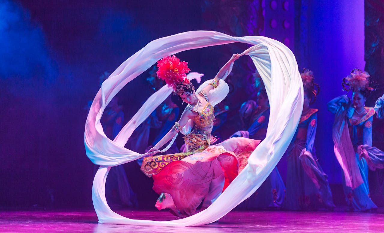 A talented dancer performs a traditional dance with flowing ribbons on a colorful stage.